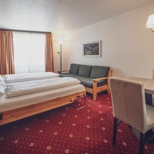 Room with double bed, sofa and dining table  | © Davos Klosters Mountains 