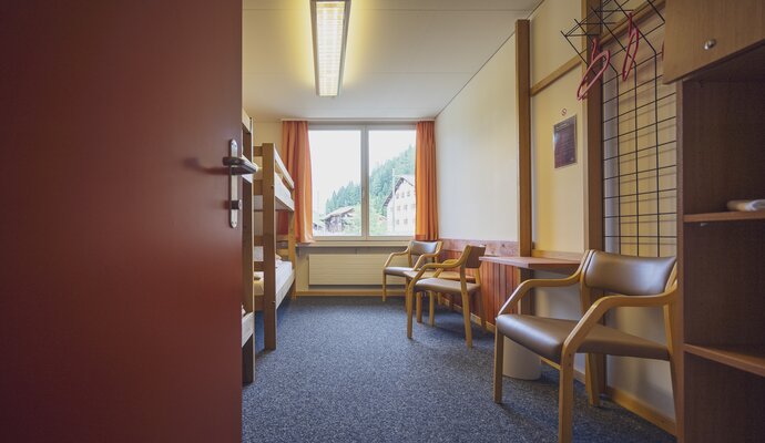 Multi-bed room with chairs and bunk beds | © Davos Klosters Mountains